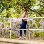 woman in blue denim jeans standing on white metal fence during daytime