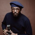 selective focus photo of man holding camera with flash