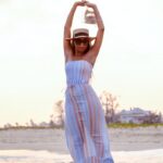 woman in white and pink stripe dress wearing white sunglasses standing on beach during daytime